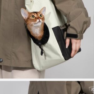 Curious cat peeks from stylish bag, complementing casual khaki jacket and showcasing pet-owner bond.