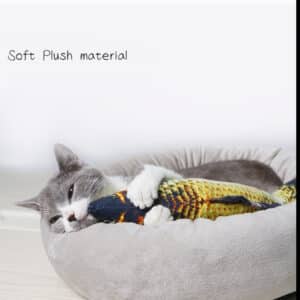 Gray and white cat playfully cuddles a colorful fish toy in a cozy pet bed.