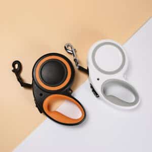 Modern retractable dog leashes in black with orange and white with grey accents.