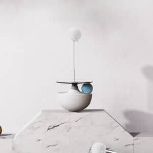 Minimalist still life with white sculpture, marble base, playful blue sphere, and fluffy pom-pom.